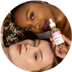 Two women lying down, one holding Her Fantasy Box Renew Her rejuvenating oil.
